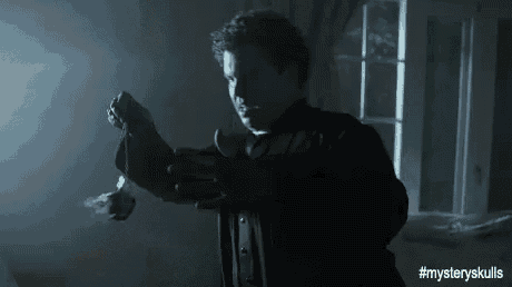 a man in a suit and tie is holding a bottle in his hand in a dark room .