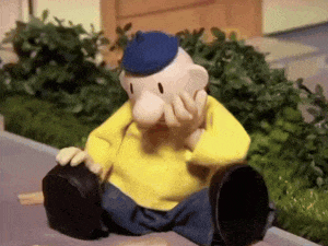 a stuffed animal is sitting on the sidewalk with his hand on his face .