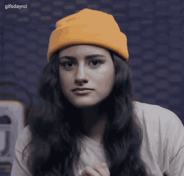 a woman wearing a yellow beanie and a white t-shirt