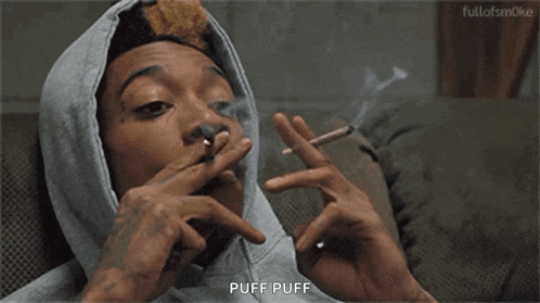 a man in a hooded sweatshirt is smoking a cigarette and saying puff puff .