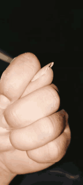 a close up of a person 's hand holding a nail
