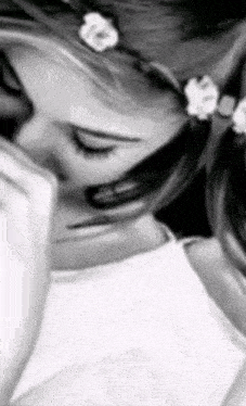 a black and white photo of a woman with flowers in her hair .