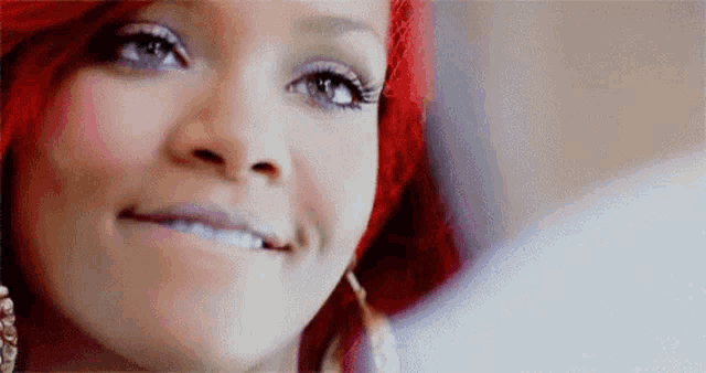 a close up of a woman 's face with red hair and blue eyes smiling .
