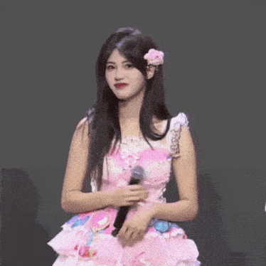 a woman in a pink and white dress holds a microphone