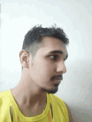 a man with a beard wearing a yellow shirt is looking down