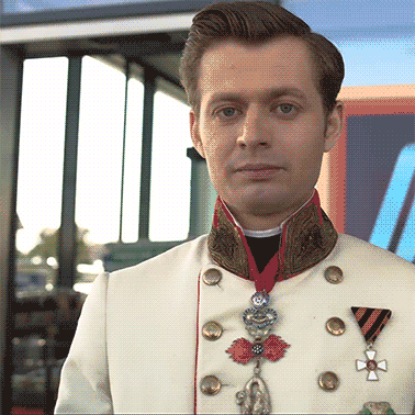 a man in a white uniform with medals around his neck looks at the camera