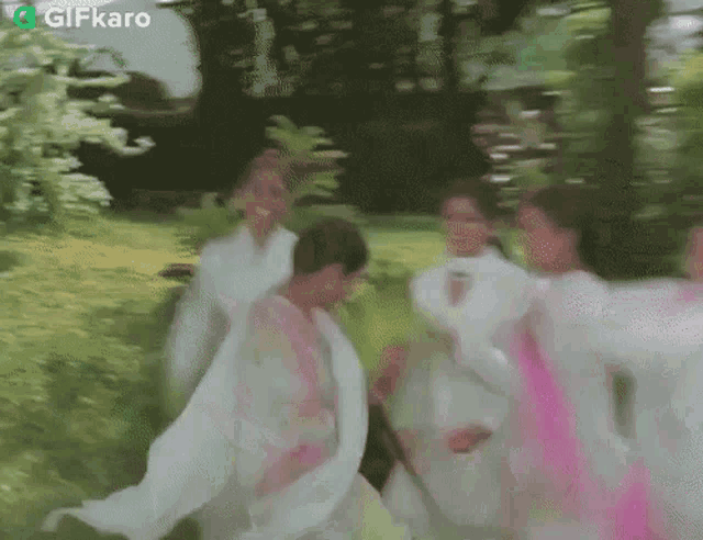 a group of women in white dresses are running through a park .