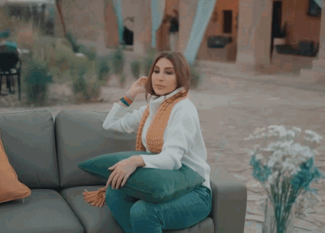 a woman is sitting on a couch with a green pillow