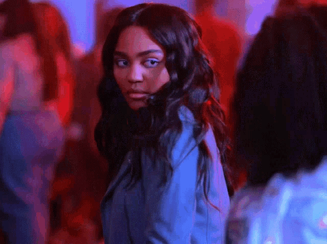 a woman in a blue jacket is standing in a crowded room looking at the camera .