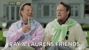 two men are sitting next to each other on a bench and laughing .