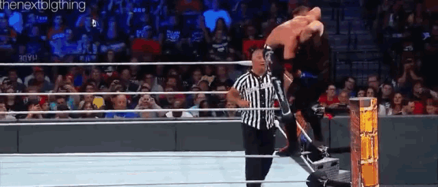 a wrestler is jumping over a rope while a referee watches