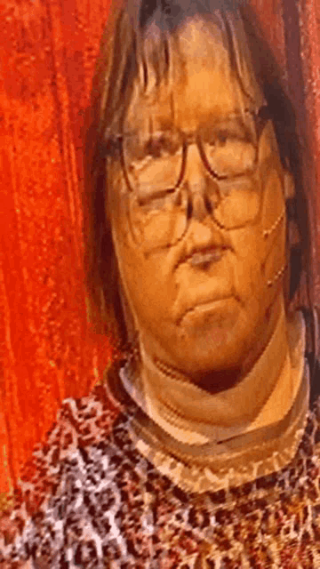 a woman wearing glasses and a leopard print sweater looks at the camera