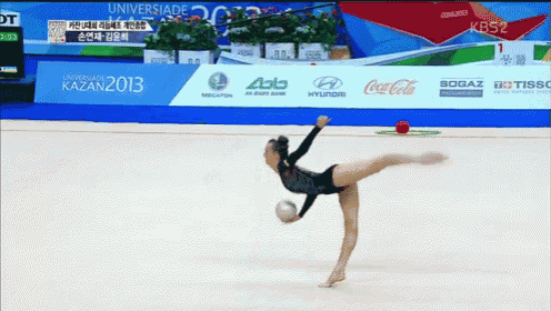 a gymnast performs a trick in front of a banner that says coca cola