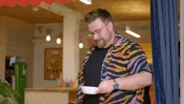 a man wearing a zebra print shirt is holding a bowl