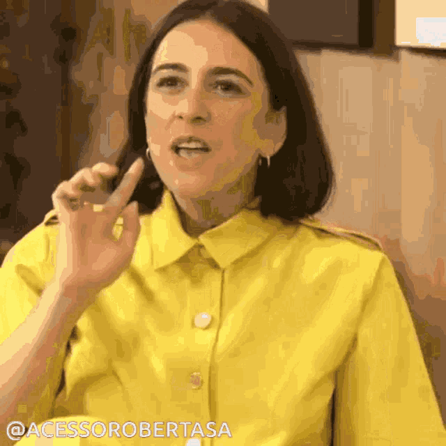 a woman in a yellow shirt is making a gesture with her finger