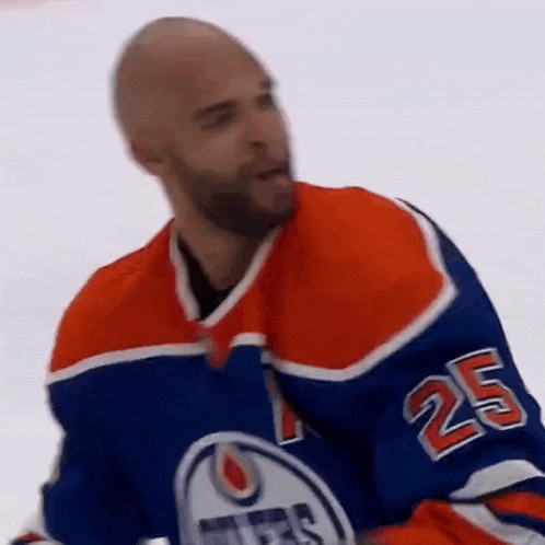 a hockey player wearing a blue and orange jersey with the number 25 on it is standing on the ice .