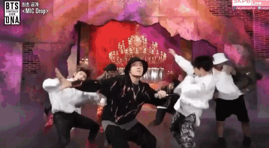 a group of young men are dancing in front of a brick wall with a sign that says bts