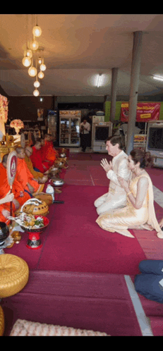 a bride and groom are kneeling in front of monks