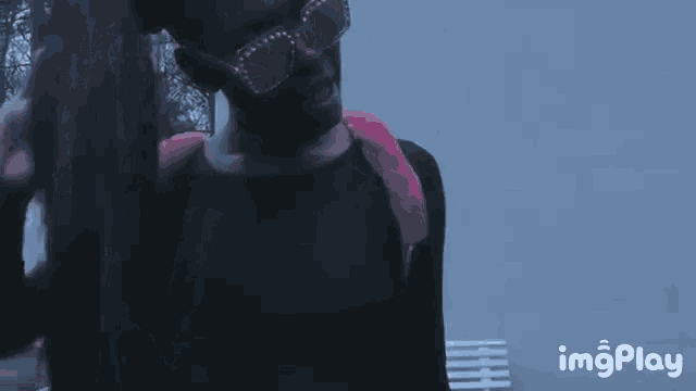 a girl wearing glasses and a pink backpack is standing in front of a blue wall .