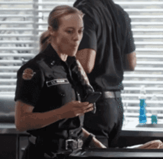 a female police officer is looking at her phone