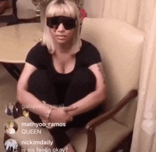 a woman wearing sunglasses sits in a chair with her knees crossed