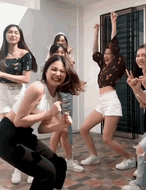 a group of young women are dancing together in a room