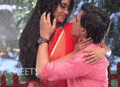 a man and a woman are kissing under the rain .