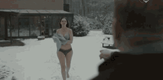 a woman in a bathing suit is walking in the snow