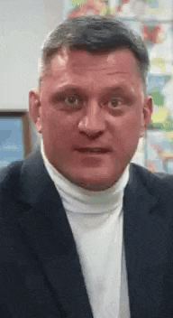 a man in a suit and turtleneck is making a funny face .