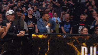 a man in a crowd wearing a shirt that says aew on it