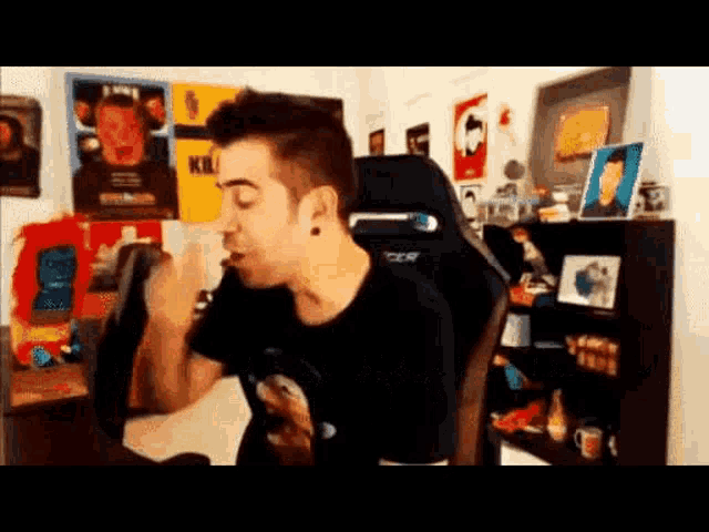 a man is sitting in a chair in a room eating a sandwich .