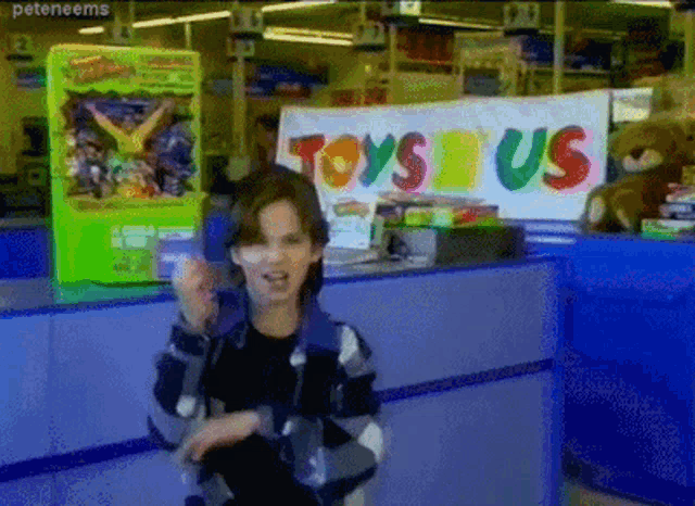 a young boy stands in front of a toys r us sign