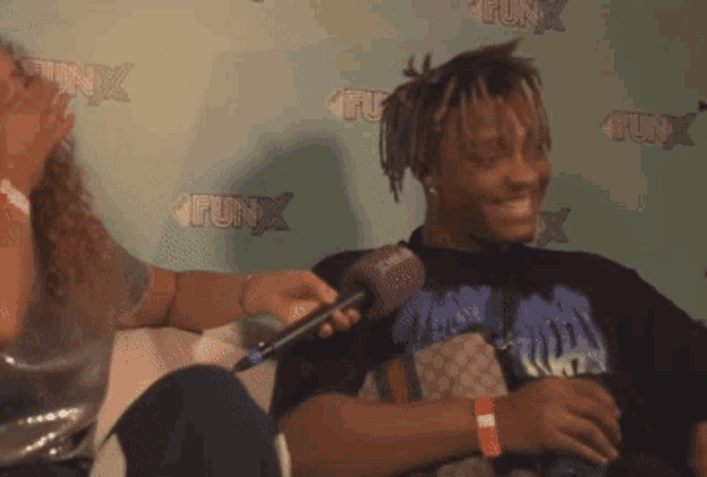 a man is being interviewed by a woman in front of a funx wall