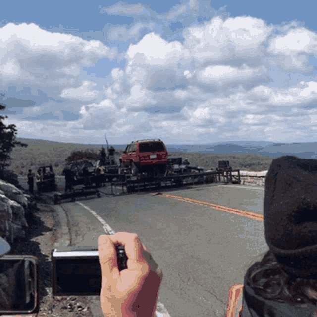 a person is taking a picture of a red suv on a trailer