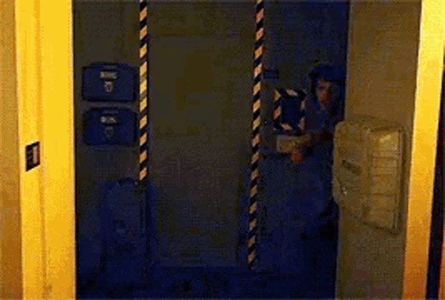 a man in a gas mask is standing in a dark room behind a door .