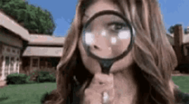 a woman is looking through a magnifying glass in front of her face .