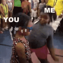 two women are dancing in front of a crowd and one of them is saying you and me