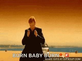 a man in a suit is standing in front of a car with the words burn baby burn above him