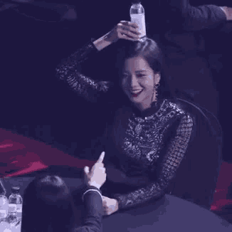 a woman is holding a bottle of water on her head .