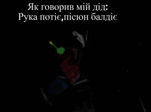 a person is holding a green object in their hand in a dark room with a foreign language written on it .