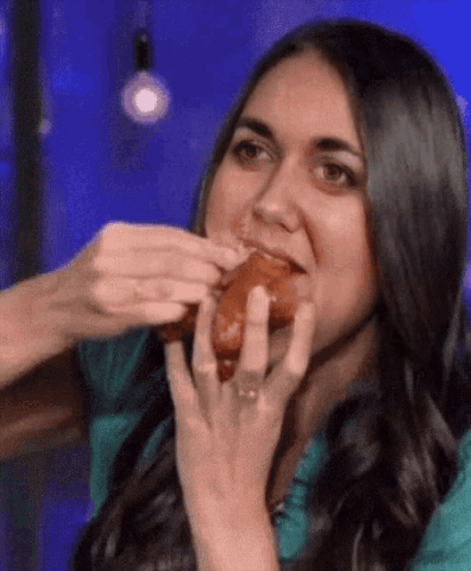 a woman in a blue shirt is eating a donut .