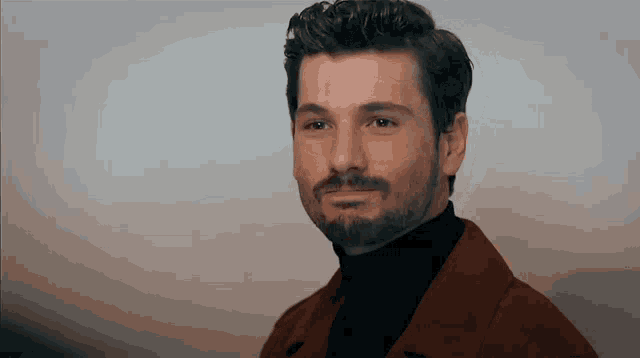 a man with a beard is wearing a brown coat and a black turtleneck