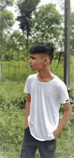 a young man in a white t-shirt is standing in a field