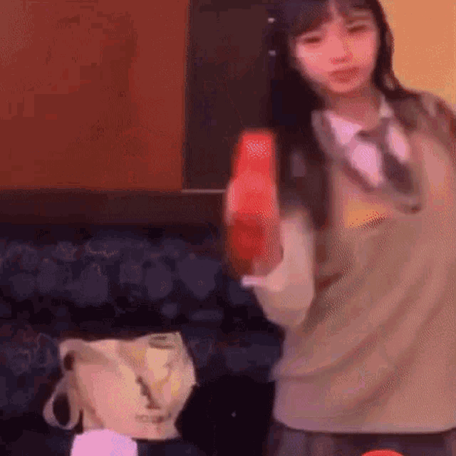 a girl is holding a red object in her hand while standing in a room .
