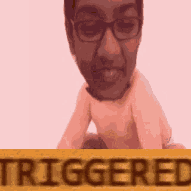 a man with glasses is sitting next to a sign that says triggered