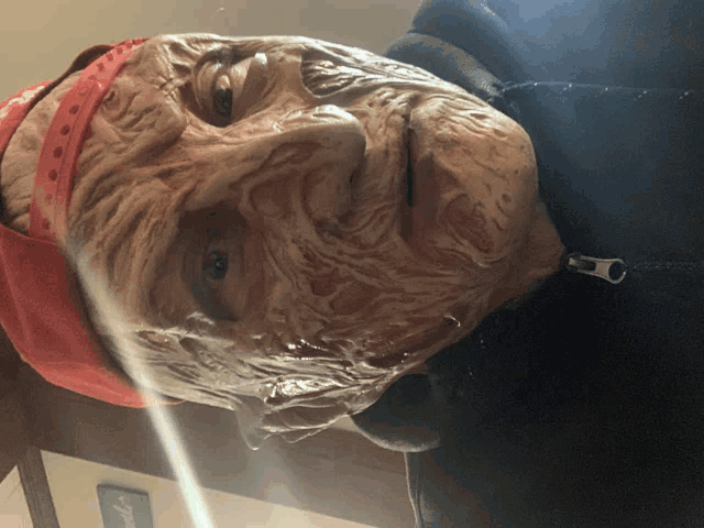 a man with a freddy krueger mask on his face is wearing a red hat