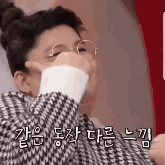 a woman wearing glasses and a plaid jacket is covering her face with her hand