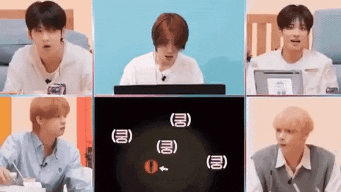 a group of young men are sitting in front of a computer screen and talking to each other .