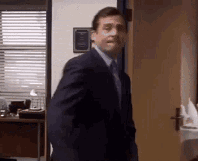 a man in a suit and tie is walking through a doorway .