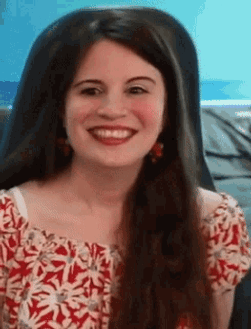 a woman with long hair is smiling and wearing a red and white shirt